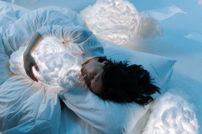 A woman in bed that sleeps deeply surrounded by shutterstock photo clouds