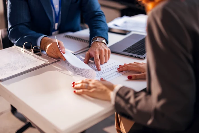 Two people read a contract before signing it