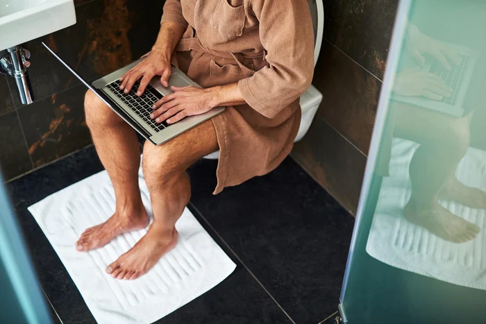 Man working on the laptop sitting on the WC Photo Study Finds DMS