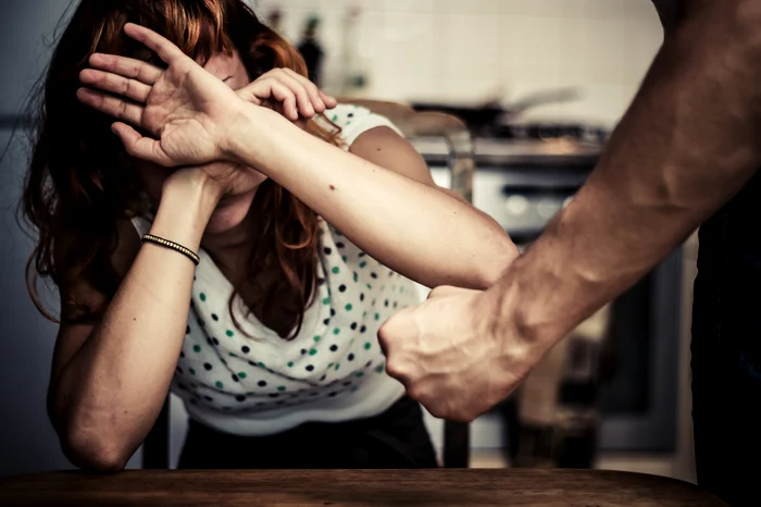 A man stands with his fist tightly in front of a woman she has already hit