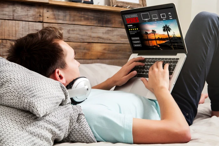 A young man looked at a series on the laptop while sitting in bed