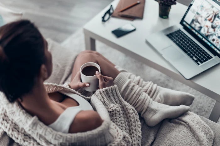 Woman relaxing on the couch in front of a laptop with a shutterstock photo cup