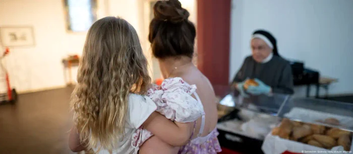 Emilya girl in her mother's arms while she gets aid from a food bank