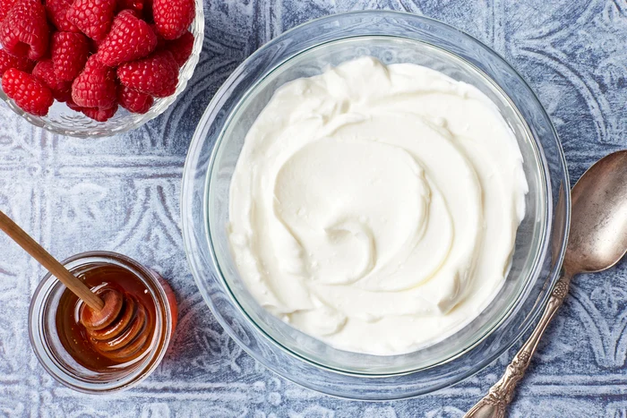 Greek yogurt bowl next to a glass of honey and a Bigger Baking Biger DMS photo bowl