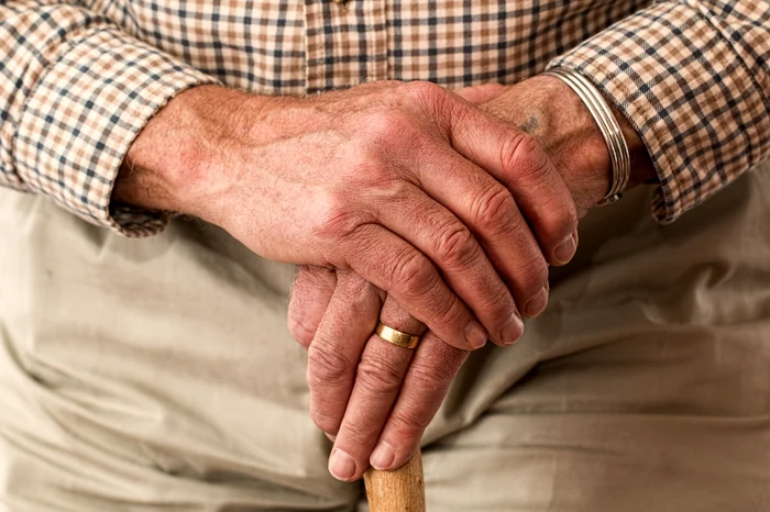 An old man holds his hands together