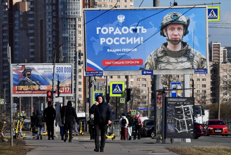 People pass by billboards promoting service in the contract army, Saint Petersburg, Russia, March 19, 2025.