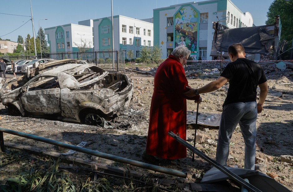A man who helps an older woman cross the destroyed street after Russia's raid to Kiev, 4 July 2025.