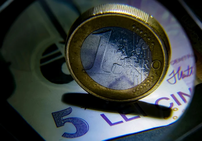 A coin of one euro over a 5 lei banknote