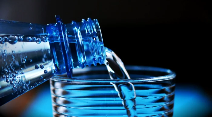 Someone pour mineral water into a glass