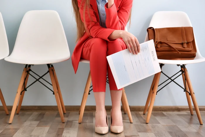 Woman dressed in a red costume with a CV in hand, in a waiting room