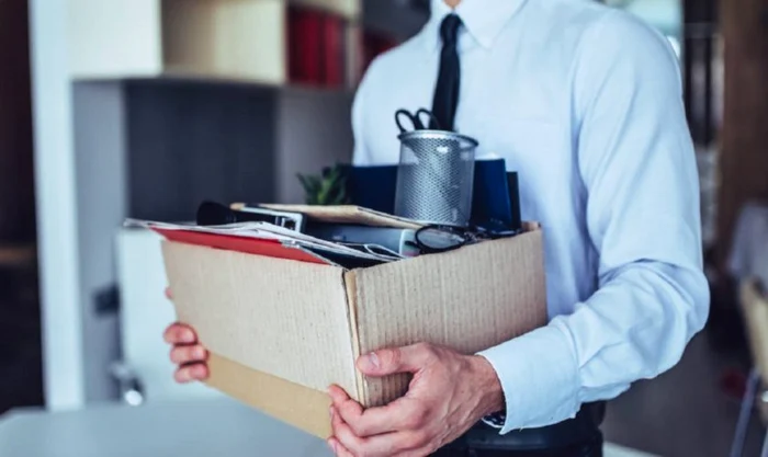 A man carries in a box of office things after being fired