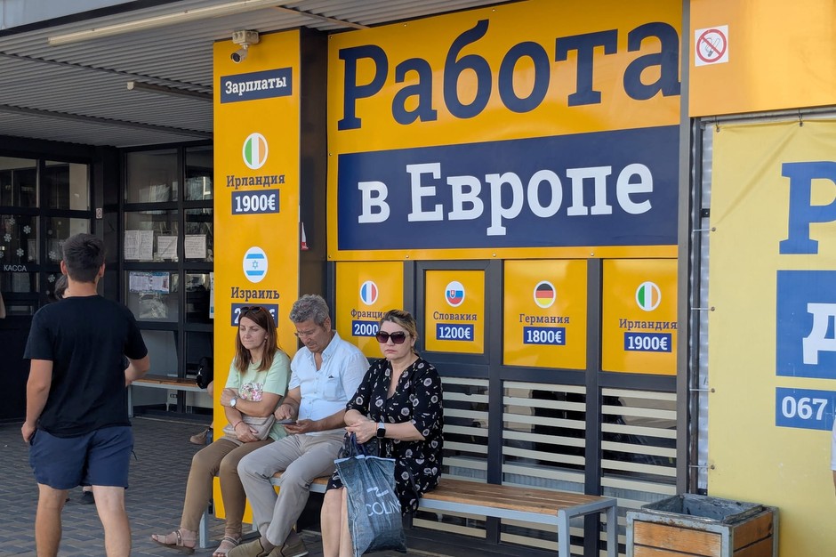 People waiting at the bus station in Komrata. Inscription in the background "Work in Europe"