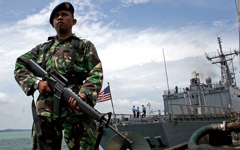 A soldier of the Indonesian Navy next to the American USS Reuben James ship in the Malakka Strait