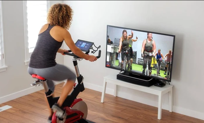Woman doing digital fitness in the comfort of home on a photo bike studiosweatdeand com