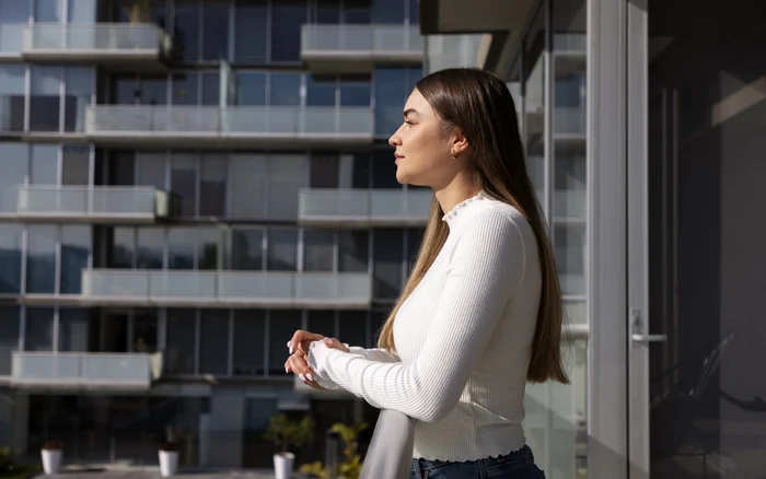 A young woman sits on the balcony of her apartment