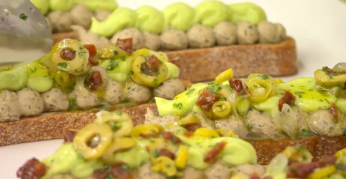 Gourmet tartina with black olive hummus, avocado cream and pickled walls