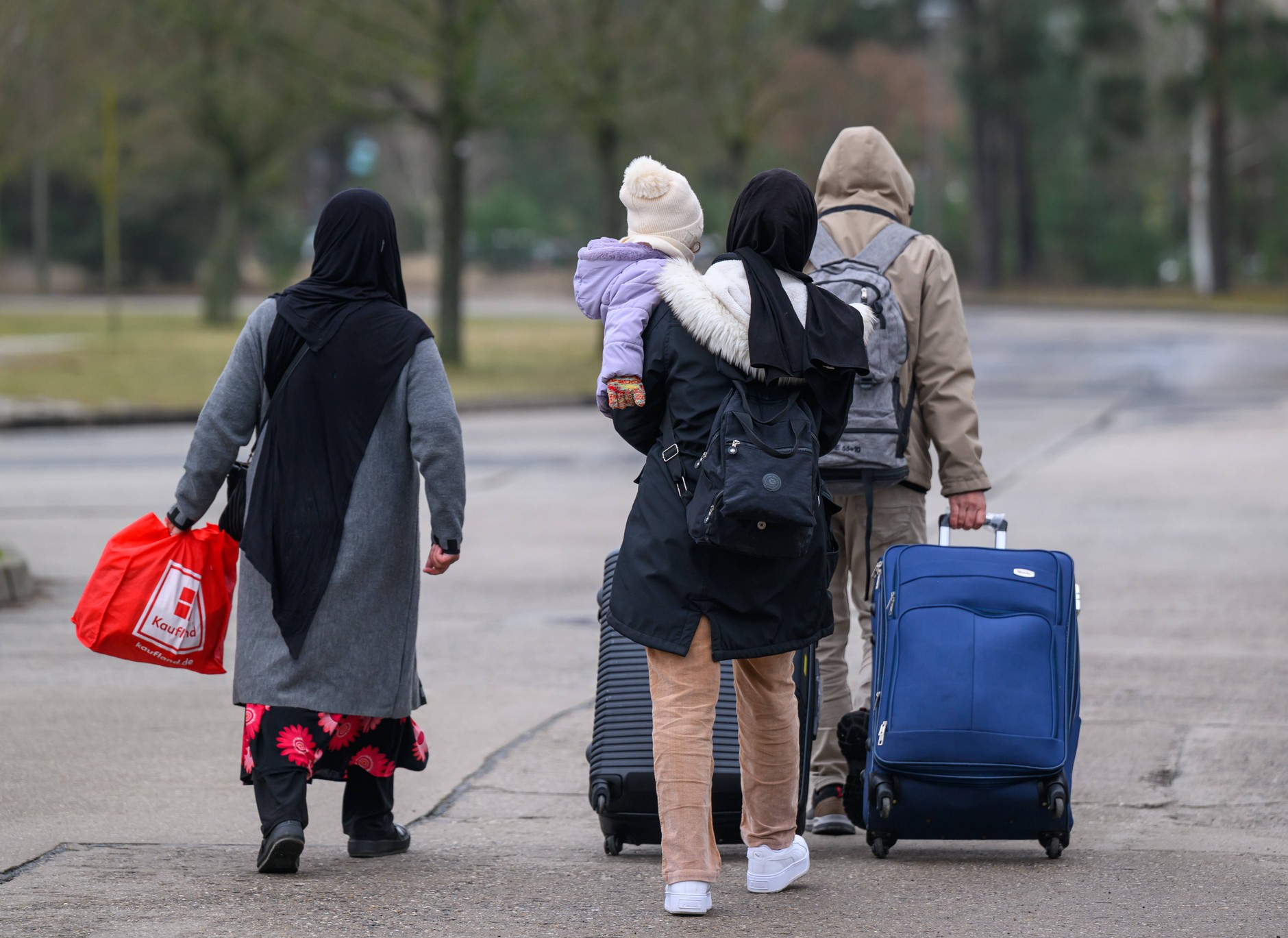 Migrants with luggage leaving the headquarters of the Central Imigration Office of Brandenburg, Eisenhuettenstadt, March 13, 2025.