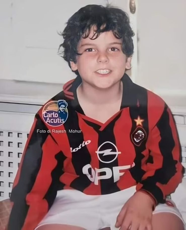 Carlo Acutis, surprised by smiling at the room, wearing AC Milan's home equipment in the 1990s.