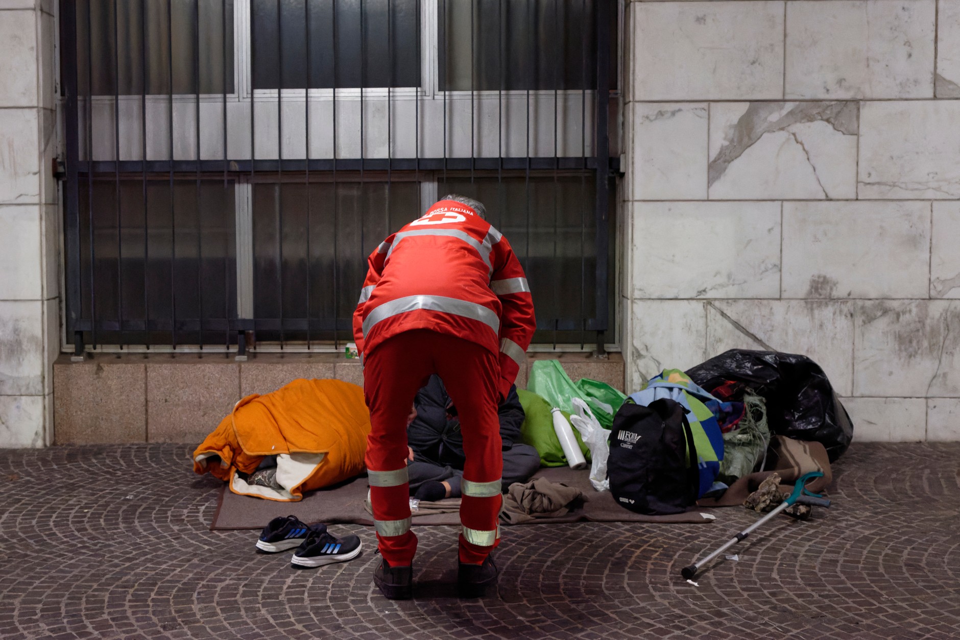 Członkowie Włoskiego Czerwonego Krzyża pomagają bezdomnemu mężczyźnie śpiącemu na ulicy podczas mroźnej zimowej nocy w Rzymie (styczeń 2024 r.)