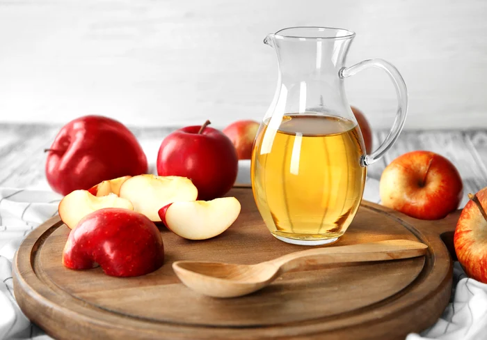A vinegar carafe surrounded by cut apples or whole photo shutterstock
