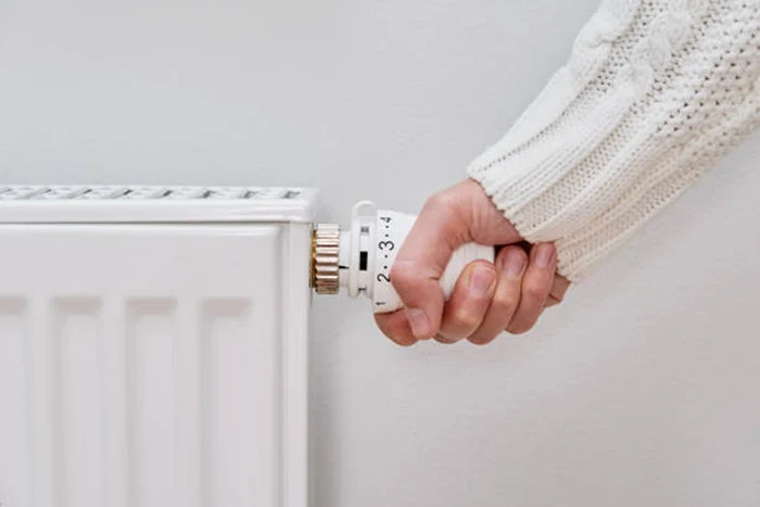 A woman adjusts the radiator thermostat