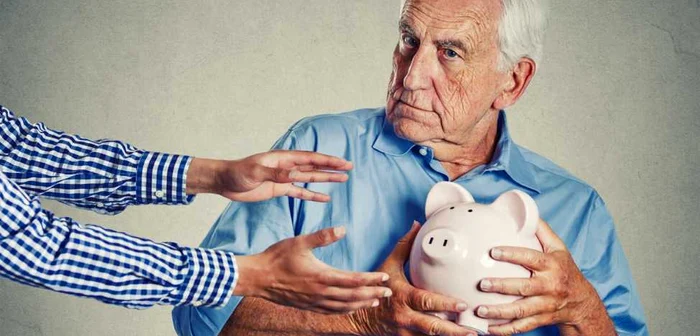 An old man clutches to his chest the piggy bank that someone wants to take