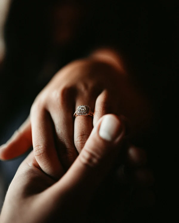 A man holds his engagement hand so that the ring is seen
