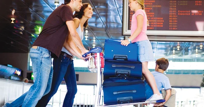A family with two children near their luggage in an airport