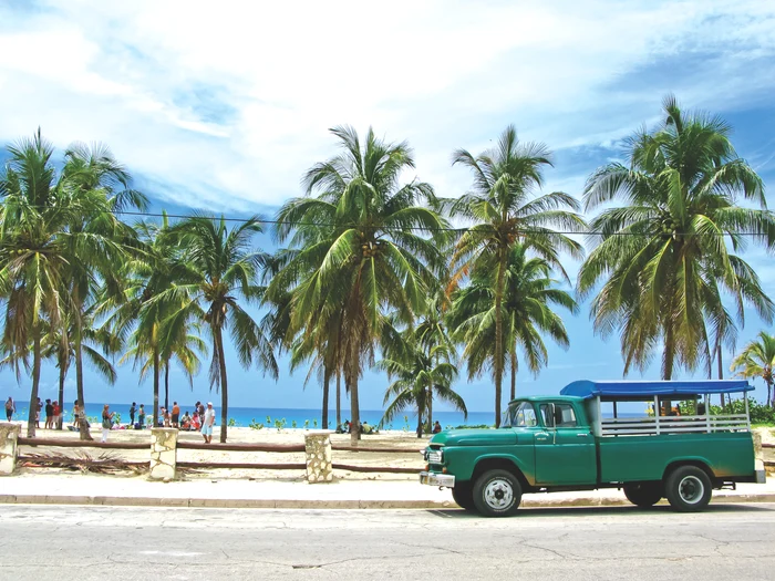 A green car near a beach in Cuba