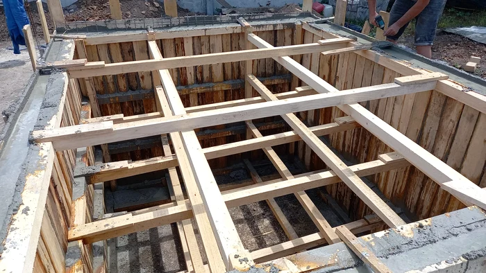Two workers make the formwork for the cellar of a country house