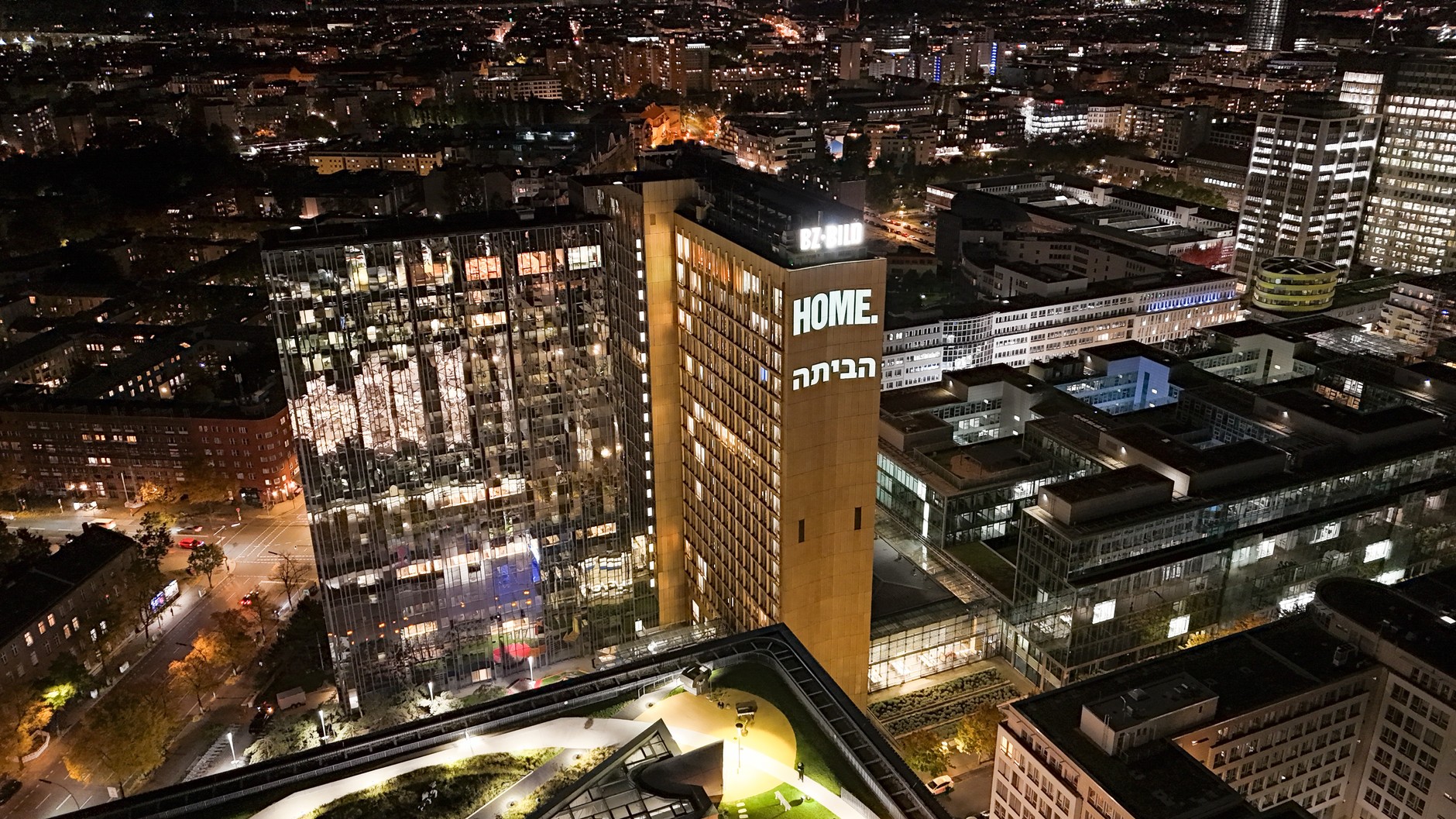 Writing "At home" in English and Hebrew displayed on the facade of an Axel Springer skyscraper in Berlin