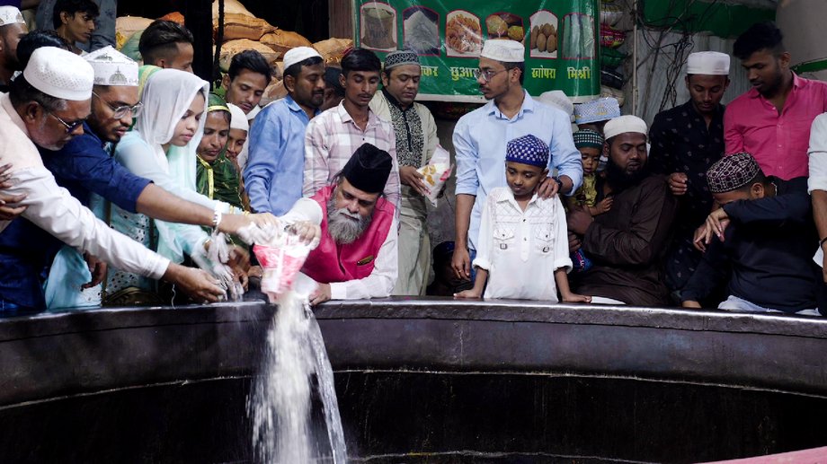 Followers who sponsor the meal gather around the cauldron to help prepare the dish