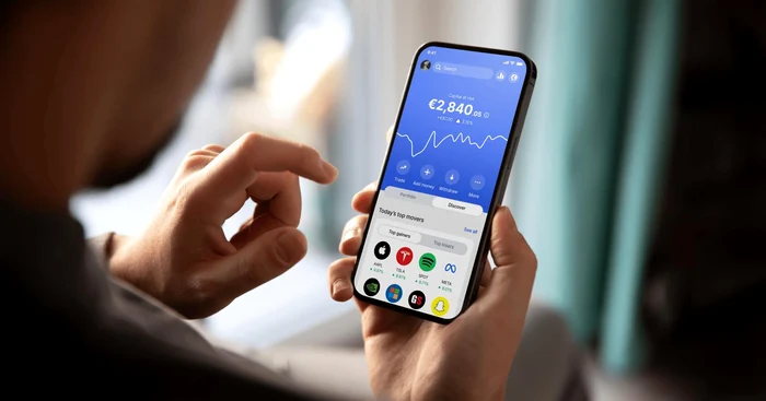 A young man watches the stock price on the stock market on his phone
