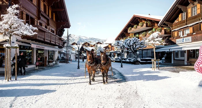 Carriage pulled by two horses on a street in a ski resort in Switzerland