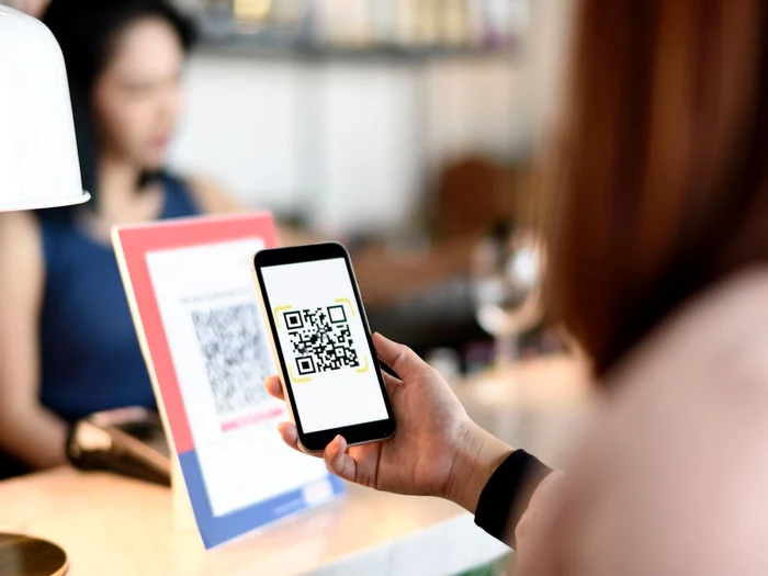 A young woman scans a QR code to pay