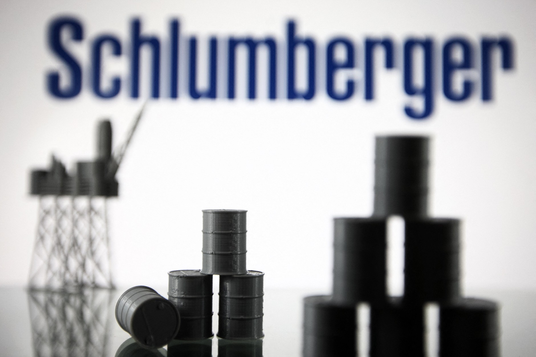 Schlumberger Limited (now SLB) logo and models of an oil rig and oil barrels, Kiev, Ukraine, August 19, 2021.