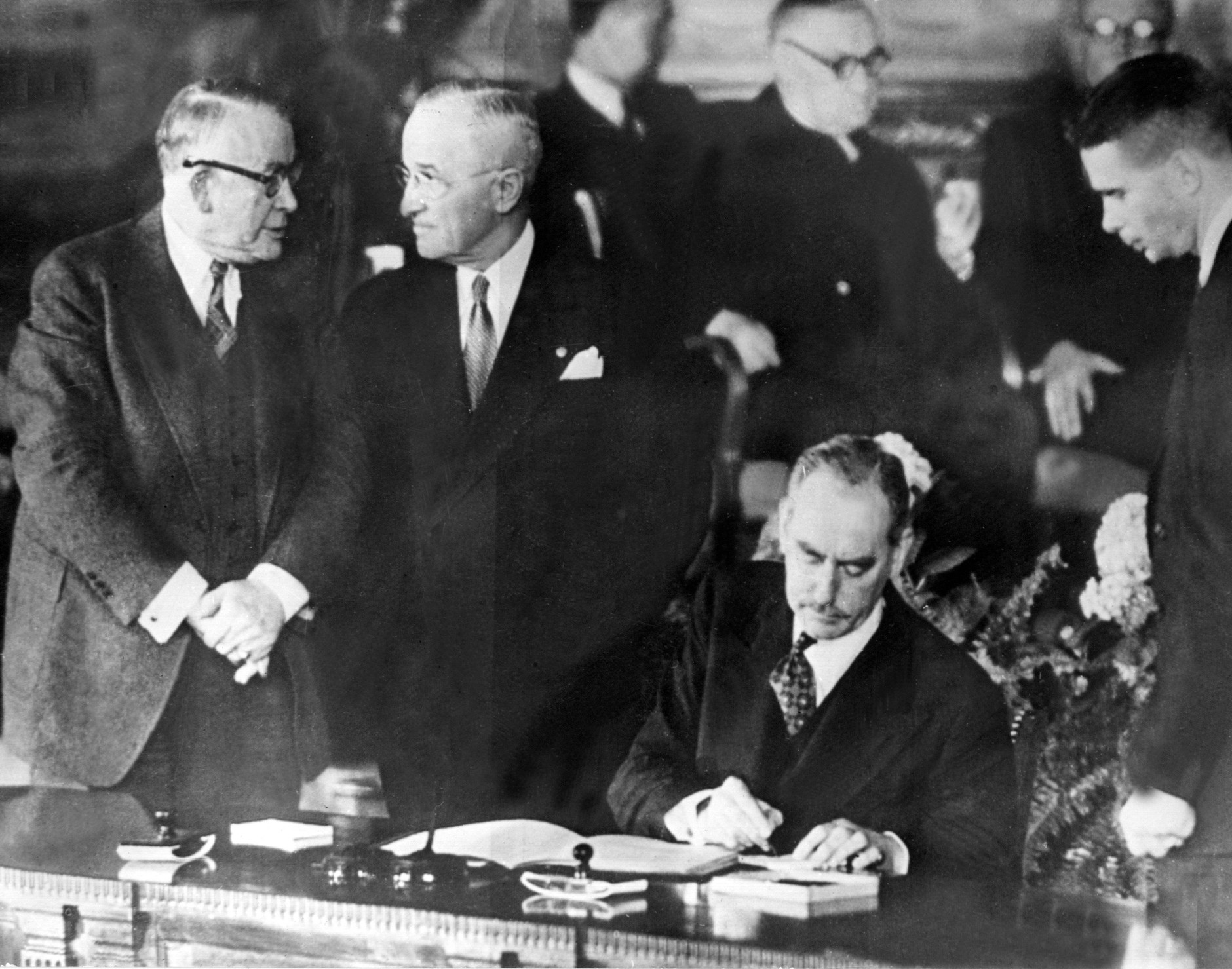 Ernest Bevin, British Foreign Secretary, Dwight Eisenhower, US President, and Dean Acheson, US Secretary of State (at his desk), during the signing of the North Atlantic Treaty. Washington, April 4, 1949