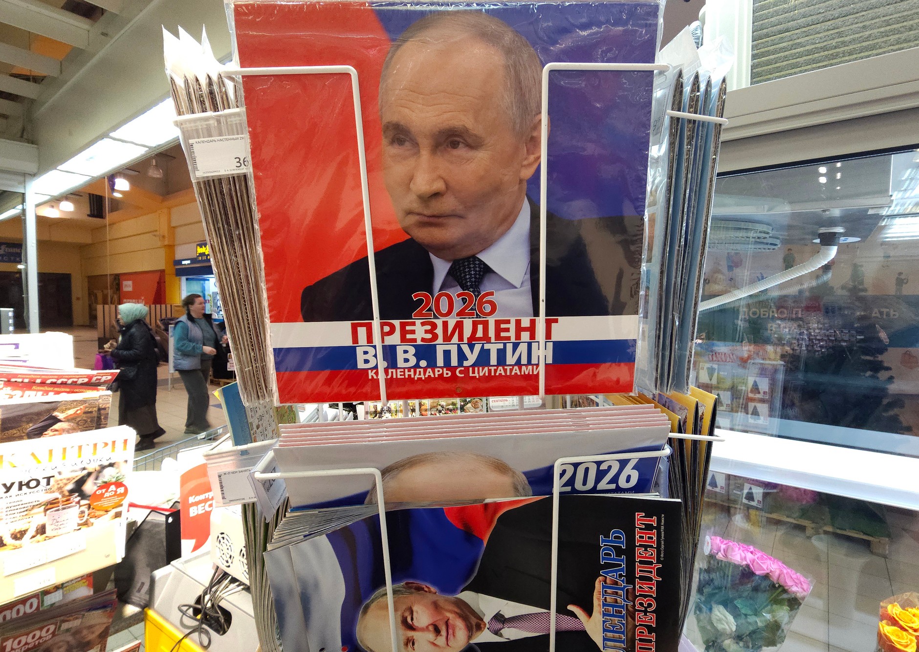 Customers walk in a supermarket next to calendars for 2026 with a portrait of Vladimir Putin, Moscow, December 6, 2025.