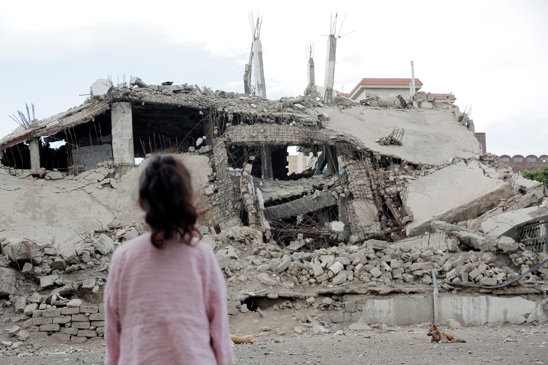A girl looks at a building destroyed by airstrikes carried out by Saudi-led coalition warplanes ahead of the ninth anniversary of the conflict, March 24, 2024. 