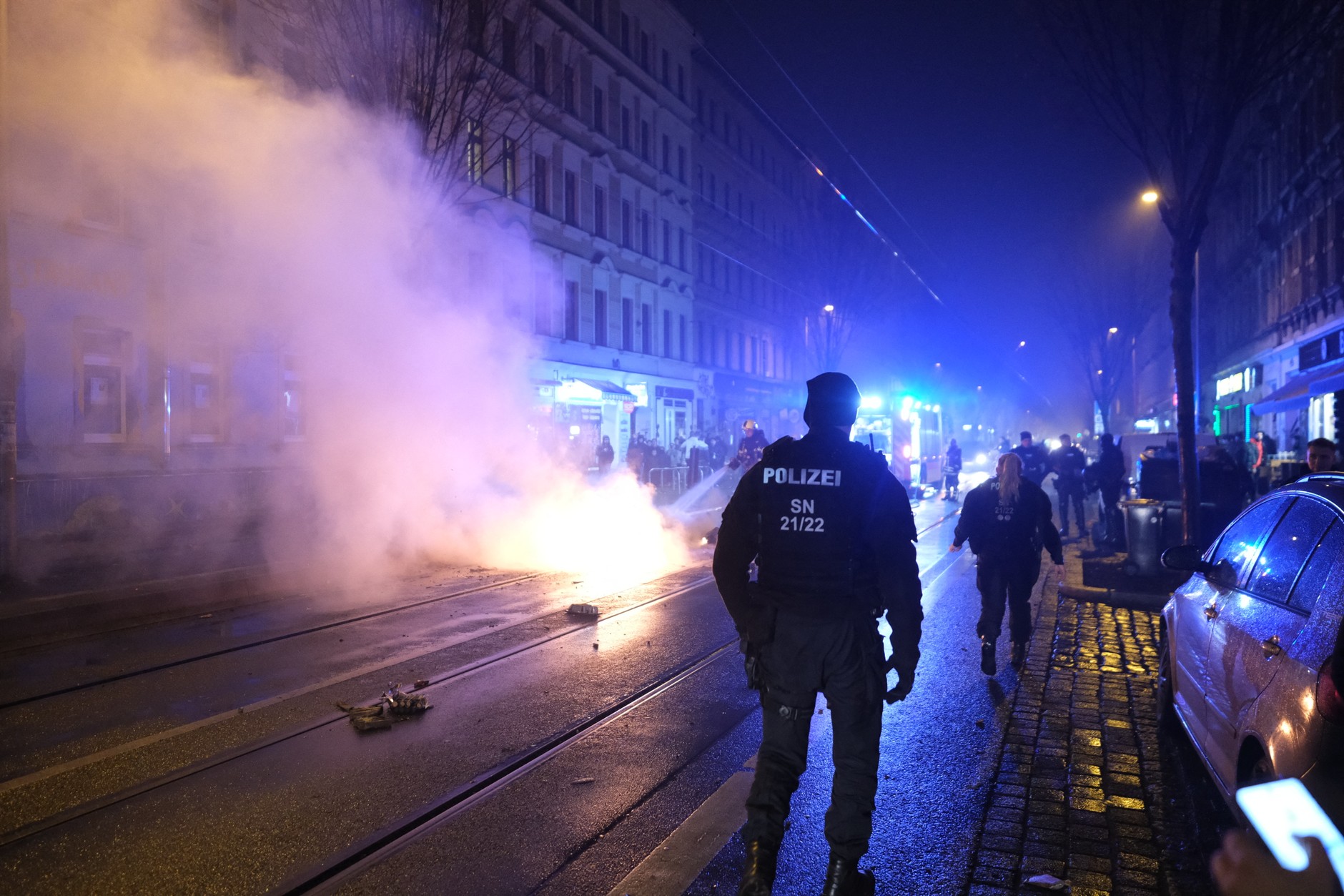 Police officers walk past a burning garbage container in the eastern part of Leipzig, January 1, 2026.