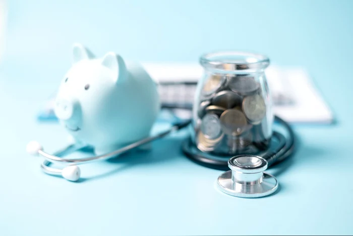 A piggy bank next to a coin jar and a stethoscope