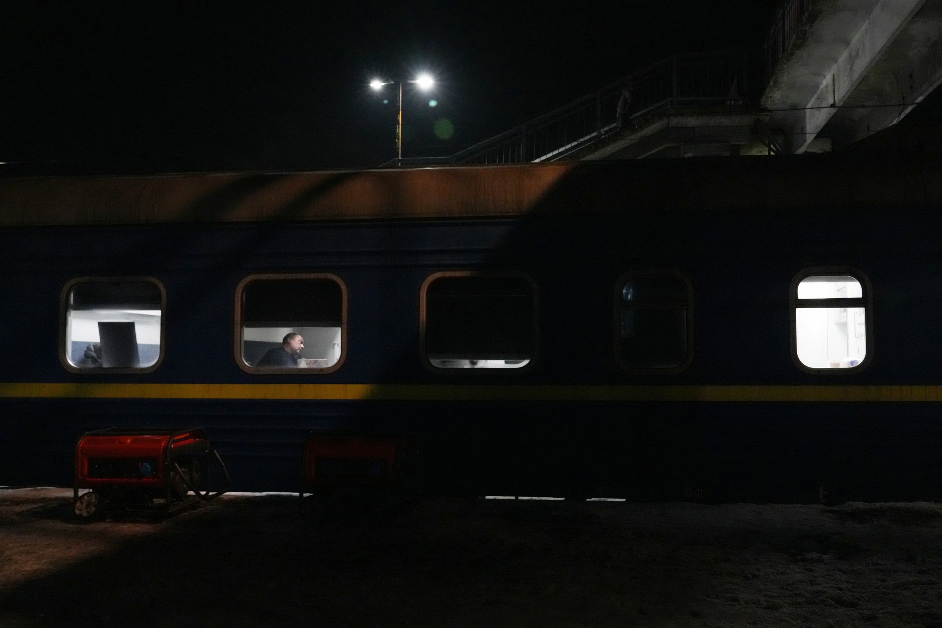 A man sits in a railway carriage temporarily used as a heating point at a railway station in the Kiev Oblast, January 21, 2026.