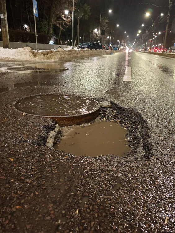 Deep hole in asphalt near a manhole cover