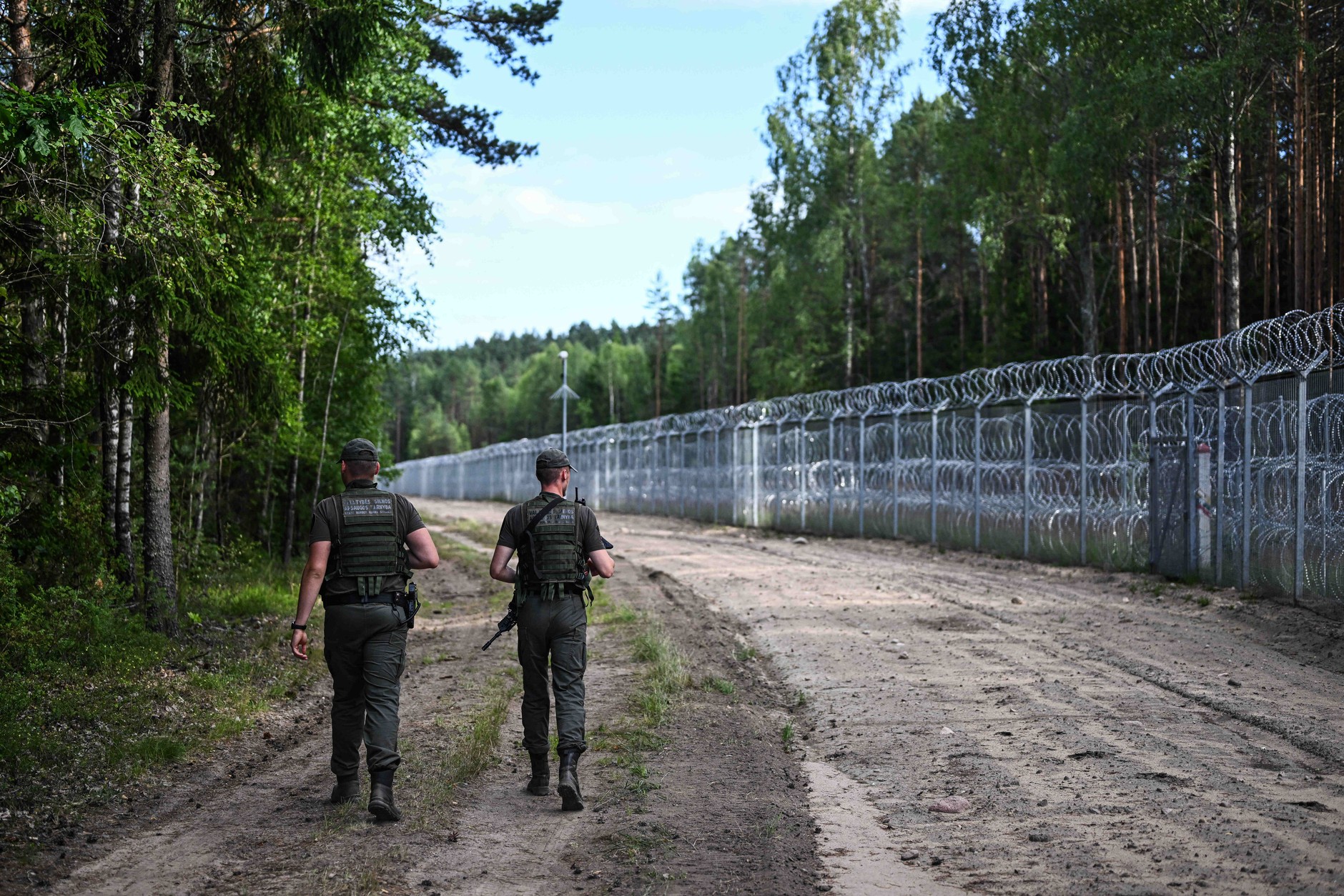Lithuanian border guards near the metal fence on the Lithuanian-Belarusian border, Dziewieniszki, July 10, 2023.