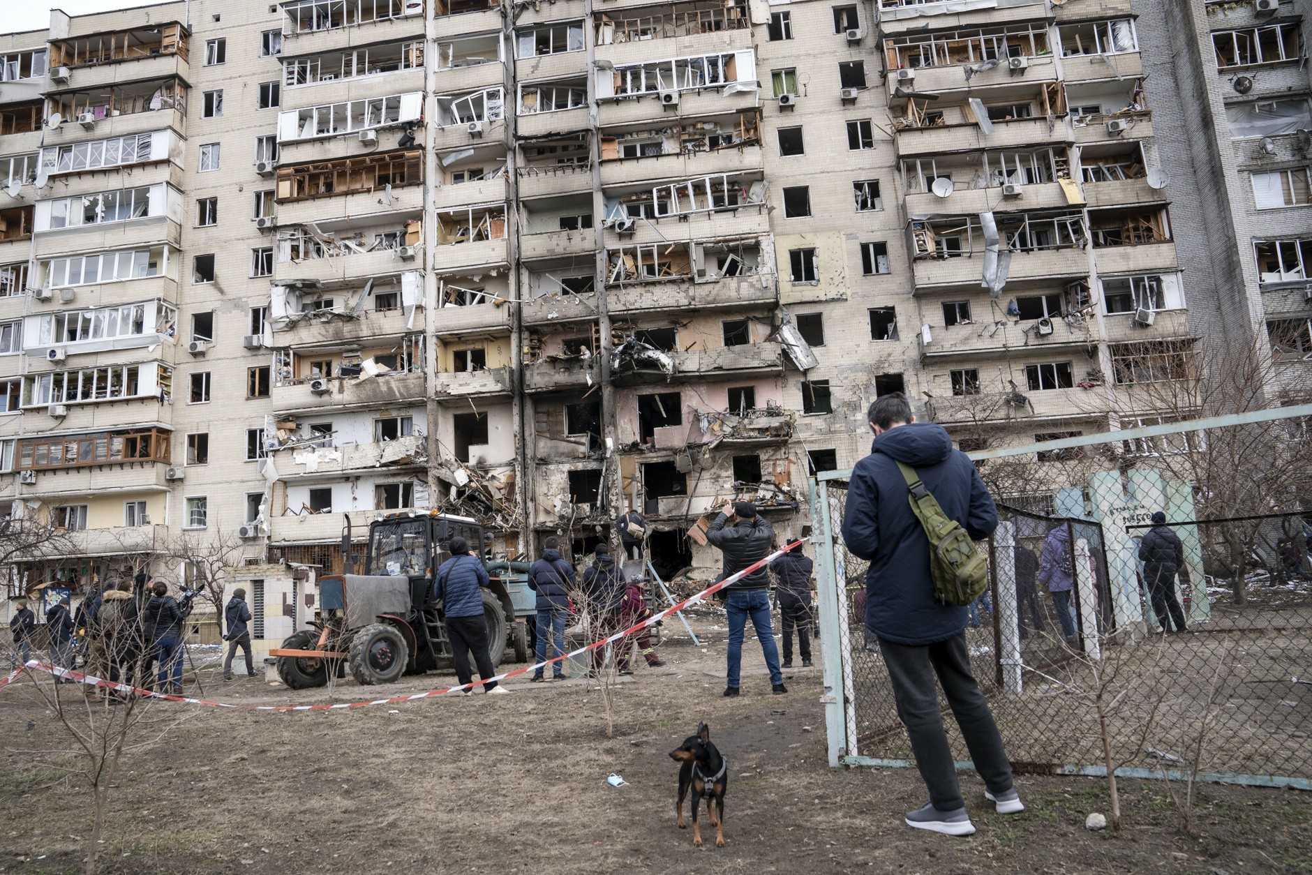 People gather in front of a building partially destroyed by shrapnel from a missile fired by Russia over a residential area in Kiev, a day after the Russian attack on February 25, 2022.