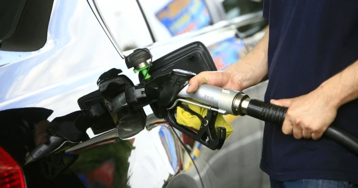 Someone fills the car with fuel at a gas station