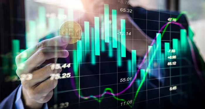 Someone is holding a Bitcoin in front of a stock chart