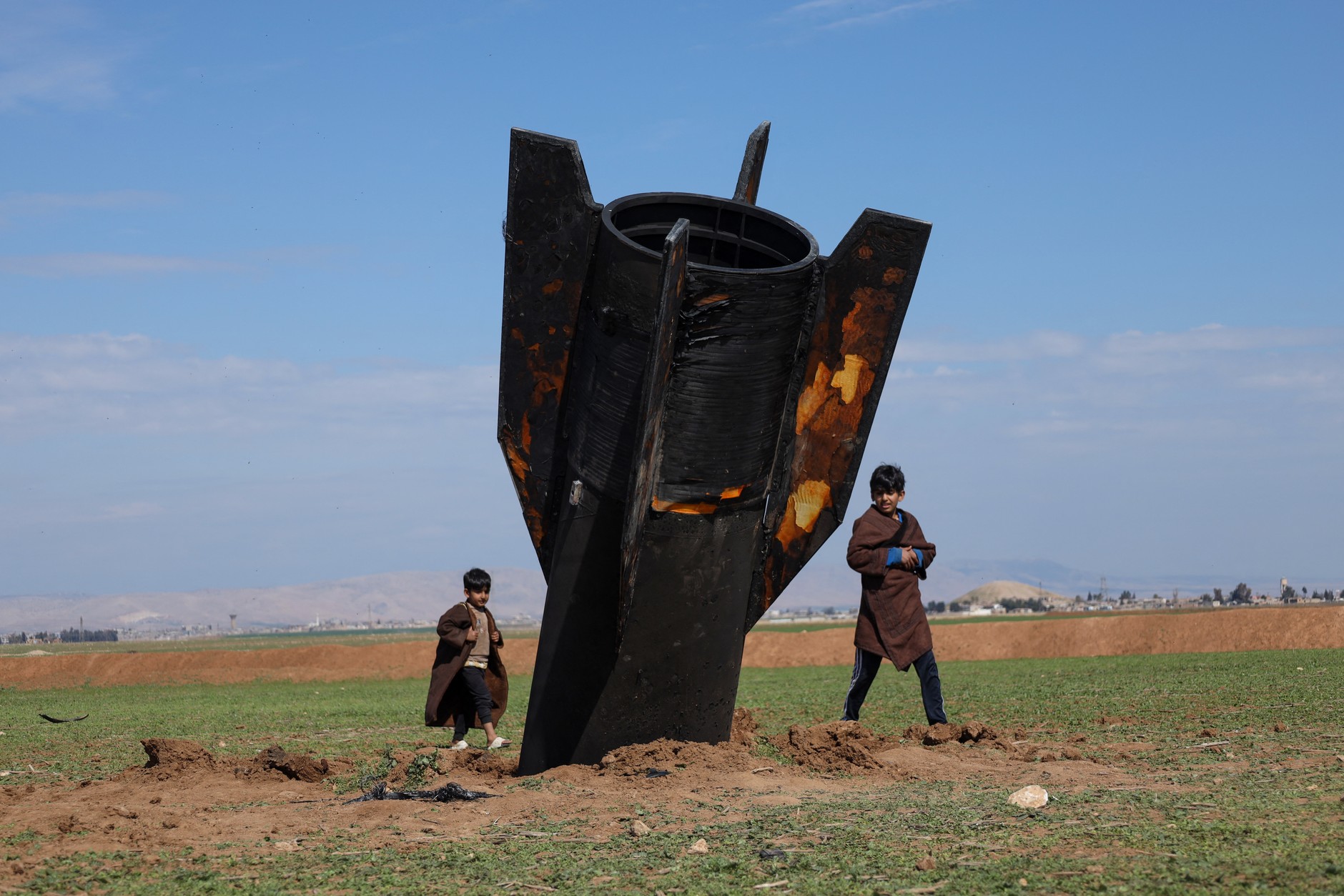 Children walk around an Iranian missile that landed near Qamishli International Airport, near the Turkish border in Syria's Hasakah province, March 4, 2026.