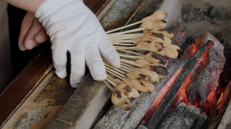 To roast the mochi, Naomi turns them until they are a uniform dark color