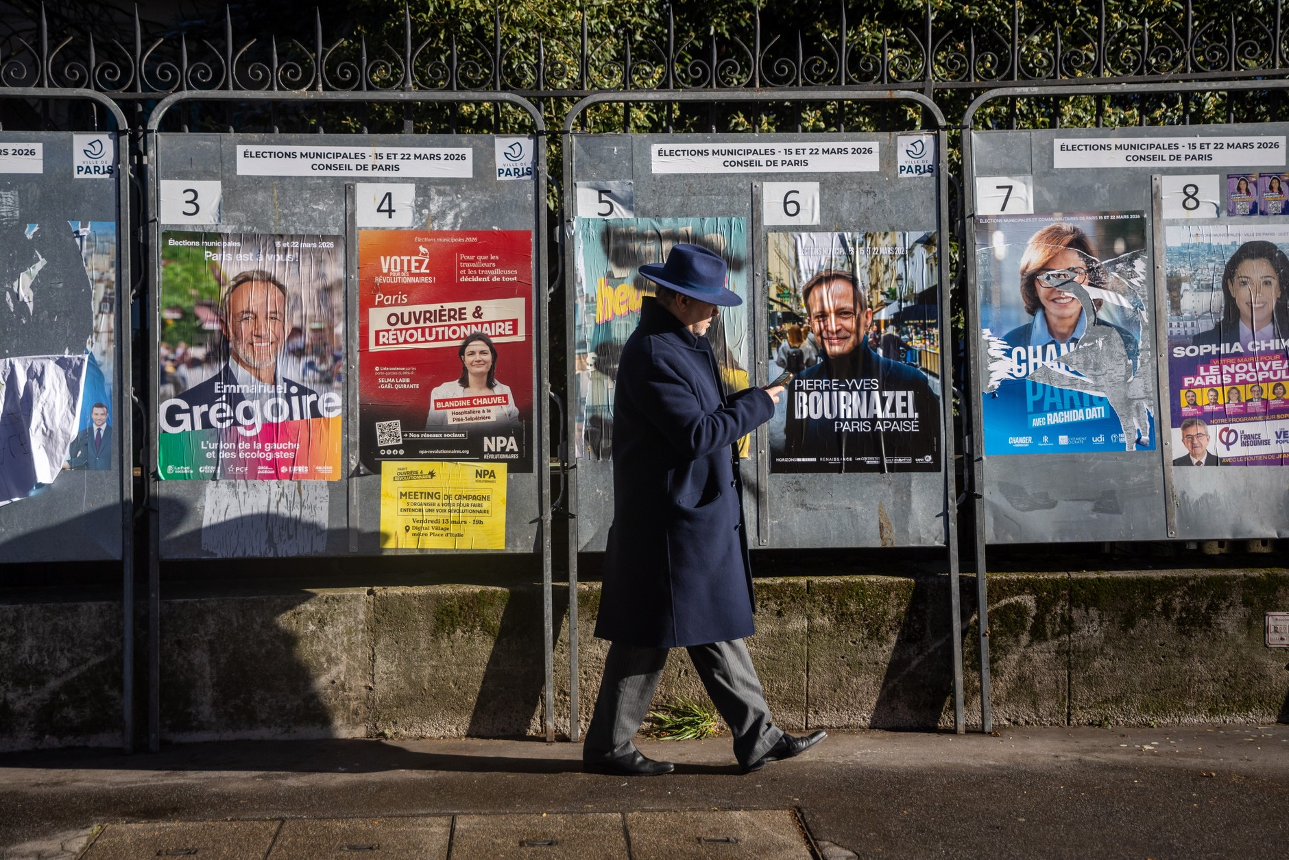 A passerby stands in front of election posters during the first round of the French municipal elections in Paris, France, March 15, 2026. 